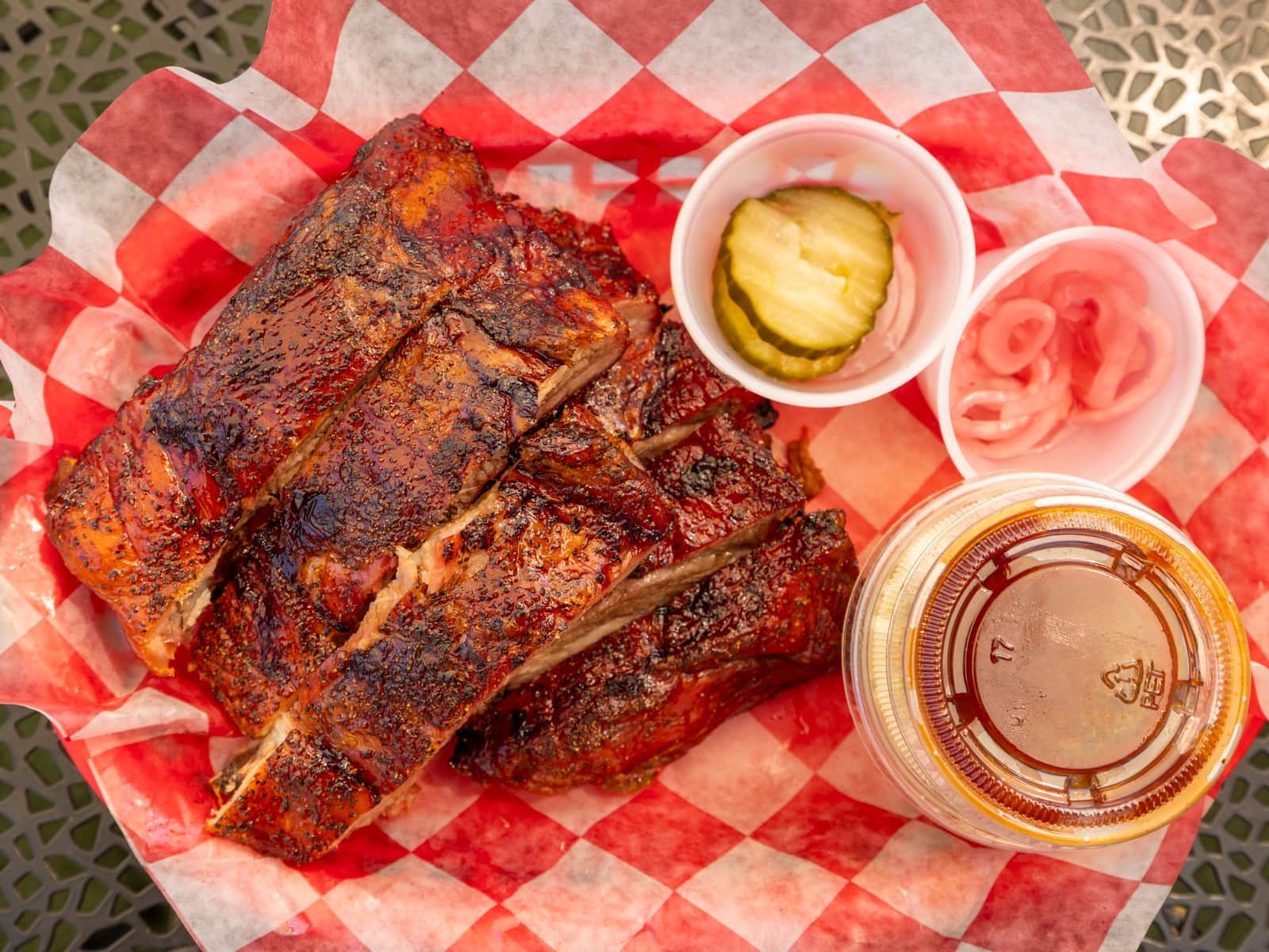 Barbecue ribs with pickles and sauce on a checked paper liner