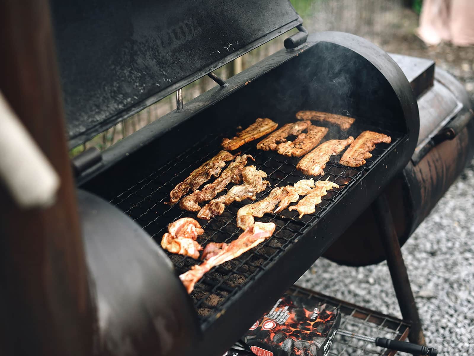Strips of meat on the grate of an offset smoker